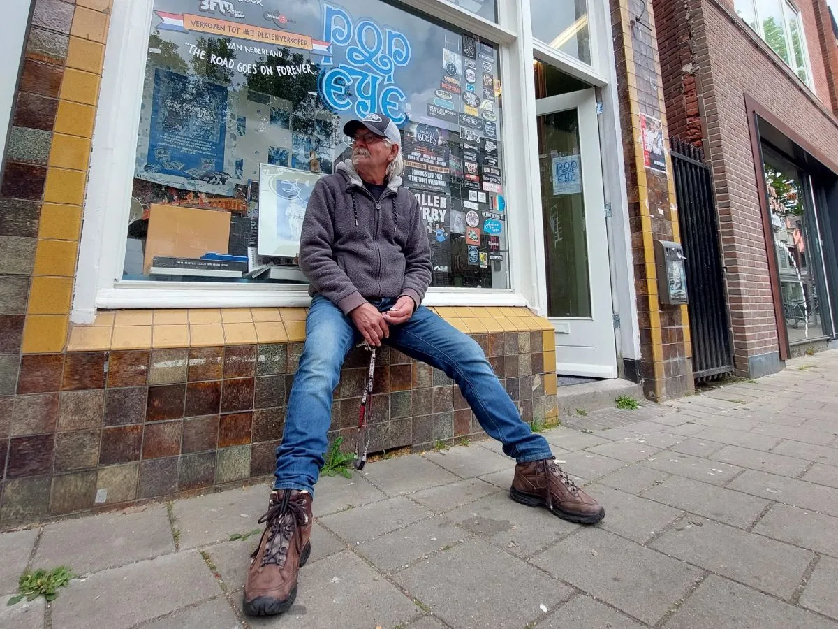 Man zit voor platenzaak op vensterbank.