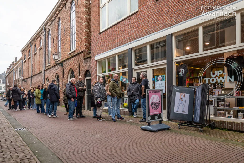 Mensen wachten in rij voor platenwinkel.