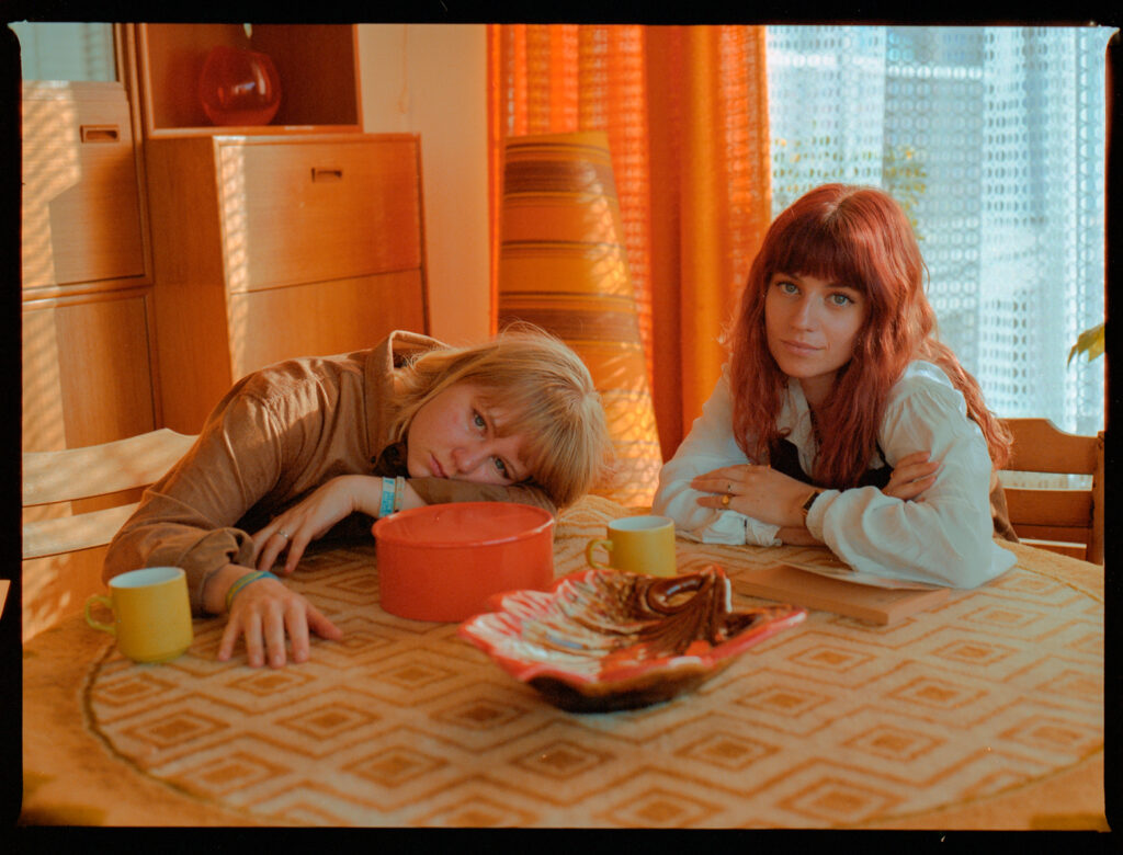 Twee vrouwen ontspannen bij retro keukentafel.