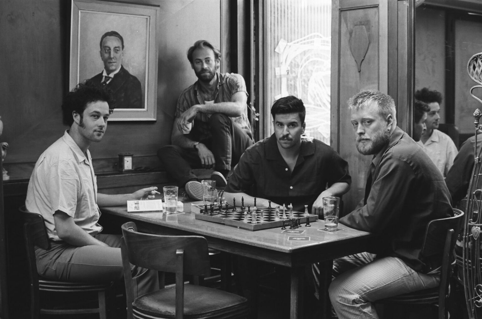 Mannen spelen schaak in café, zwart-wit foto.