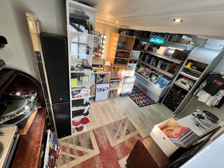 Binnenkant retro platenzaak met vinyl en posters.