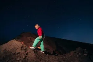 Persoon wandelt 's nachts onder sterrenhemel.