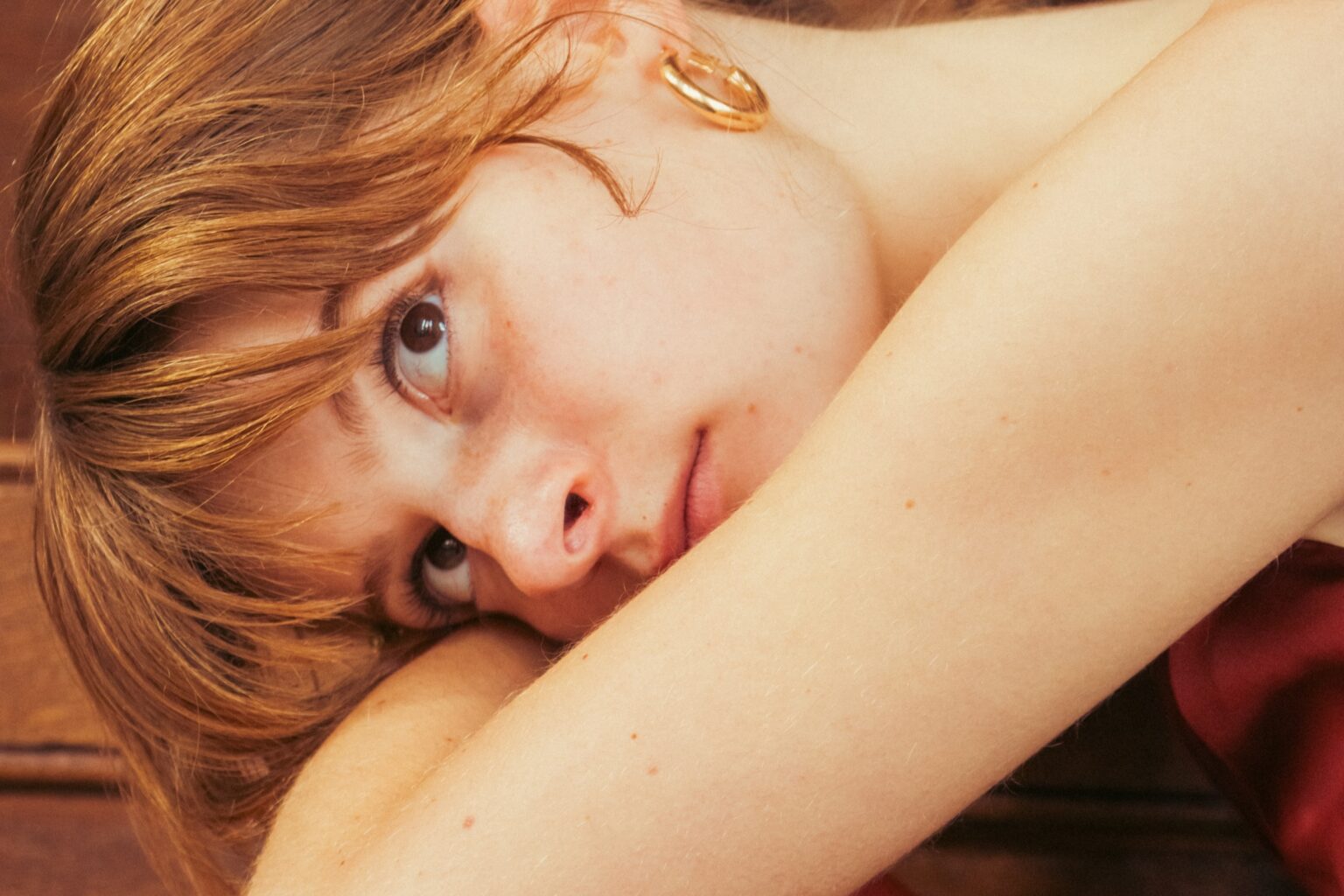 Vrouw met bruin haar en gouden oorbel.