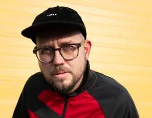 Man in modieuze jas voor gele muur