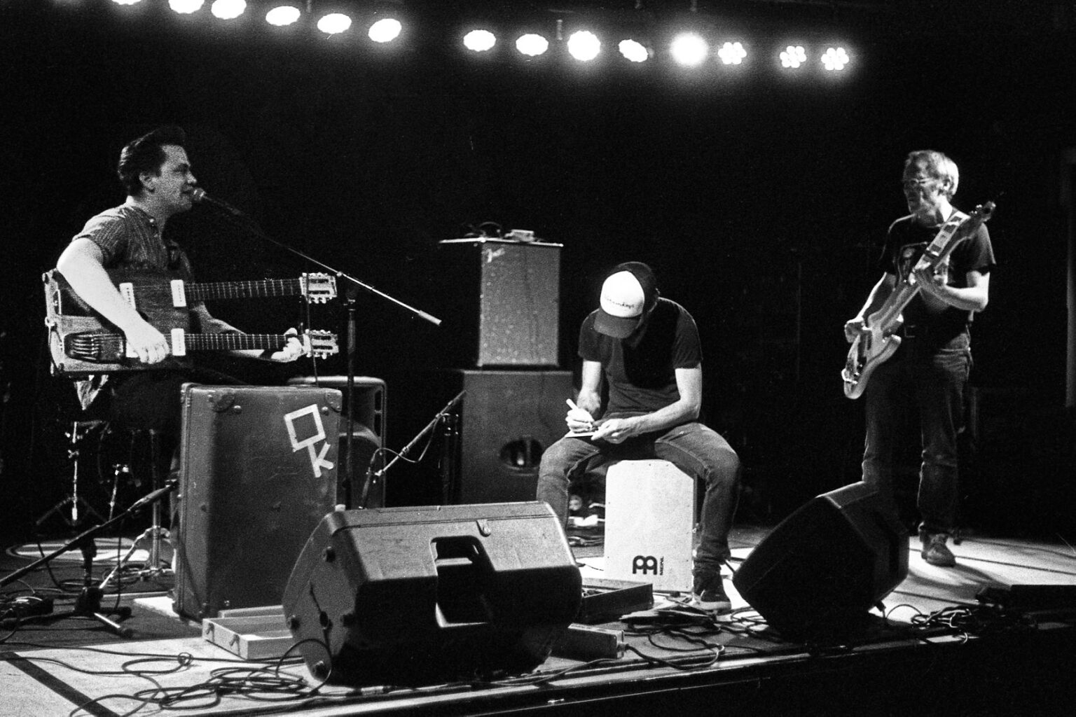 Muzikanten spelen live op podium in zwart-wit.