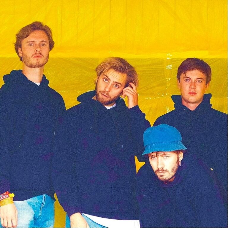 Vier mannen voor gele achtergrond, casual gekleed.