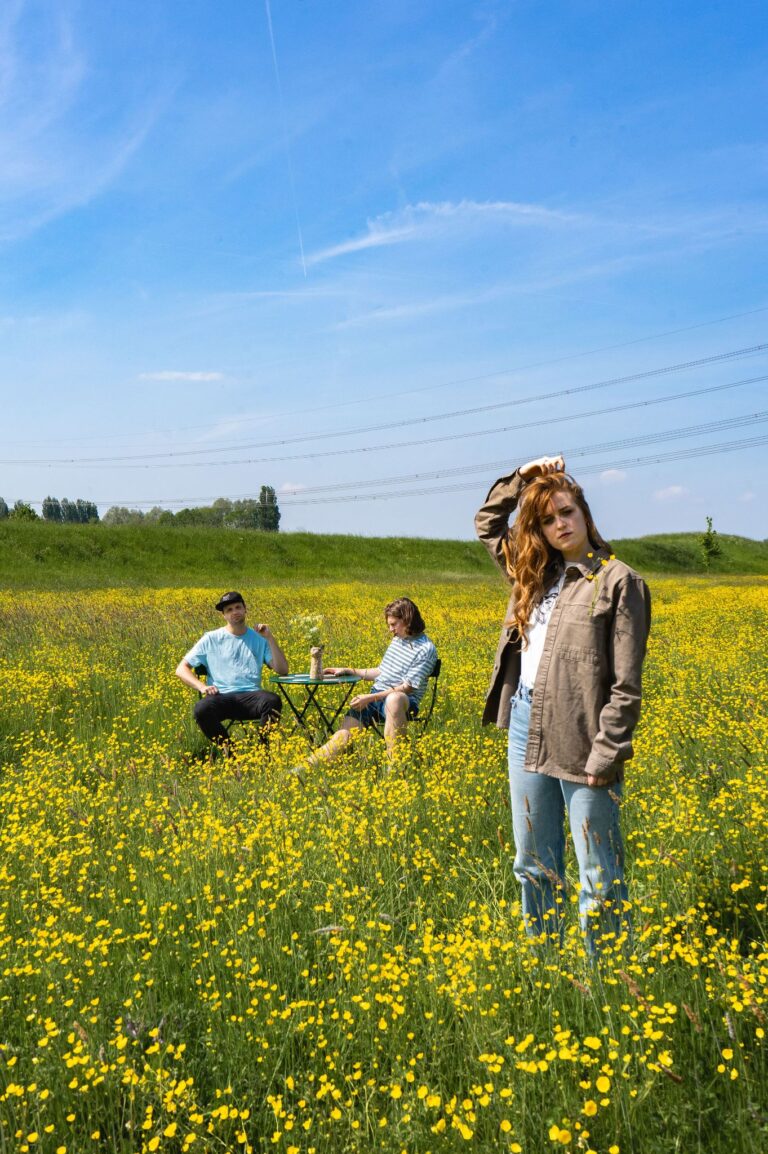 Drie mensen in bloemenveld op zonnige dag