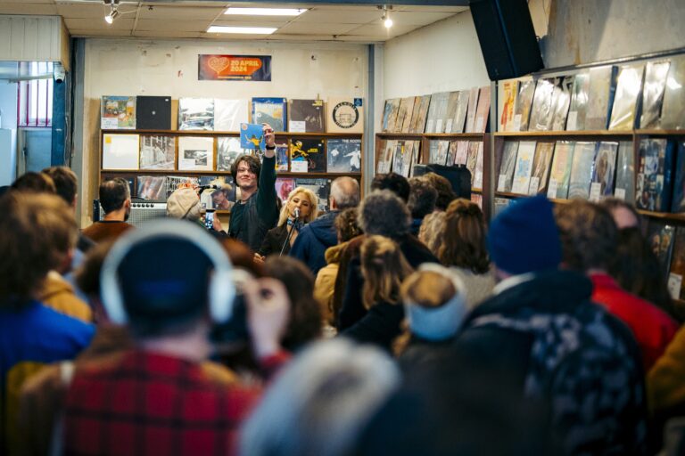 Muziek optreden in drukke platenwinkel met publiek.