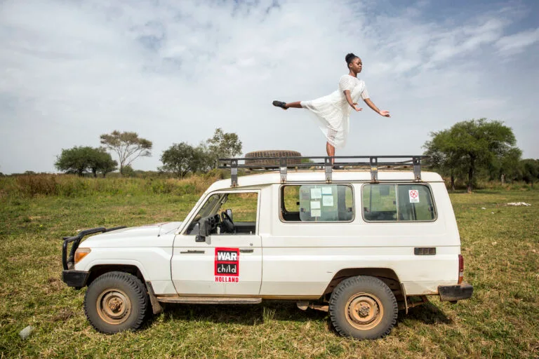 Balletdanseres op jeep in natuurveld