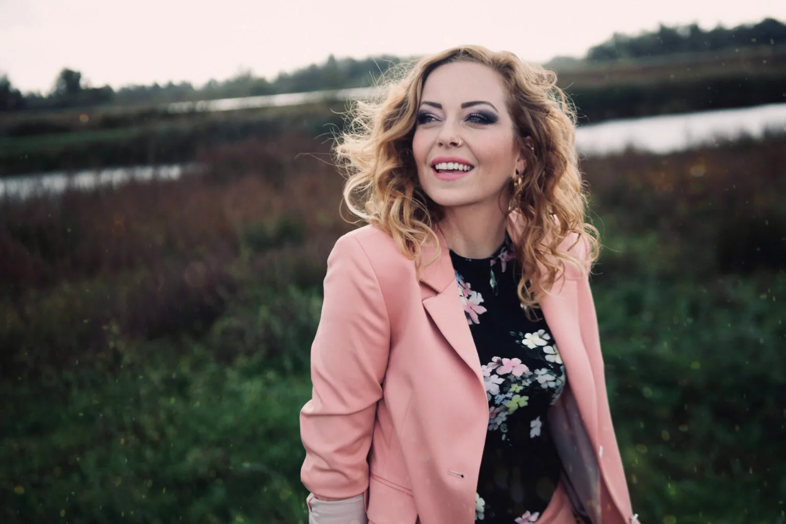 Vrouw in roze blazer buiten met lachend gezicht