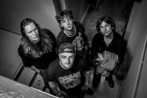 Vier mannen poseren op trap, zwart-wit foto.