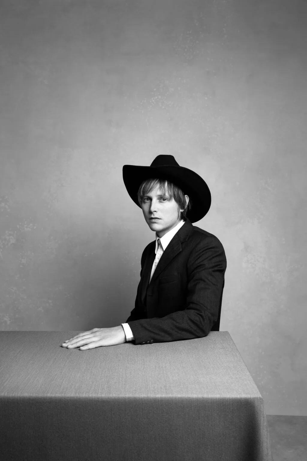 Man in pak met cowboyhoed aan tafel.