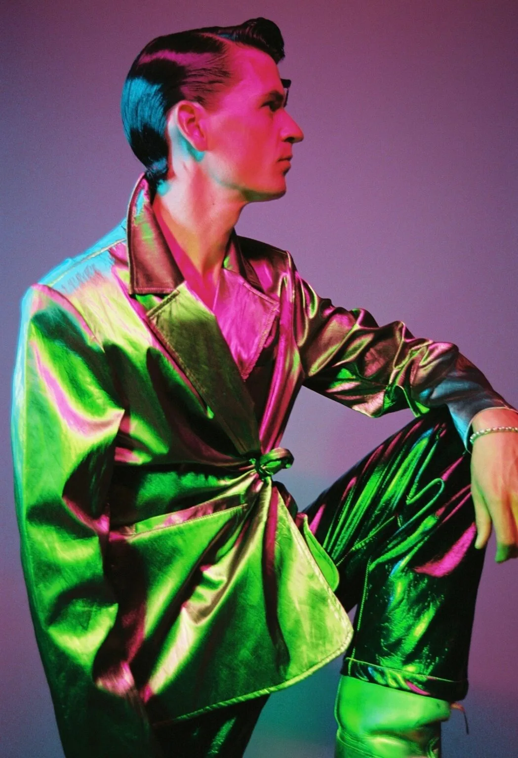 Man in metallic outfit met kleurrijke belichting.
