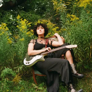 Persoon met gitaar zittend in bloemenveld