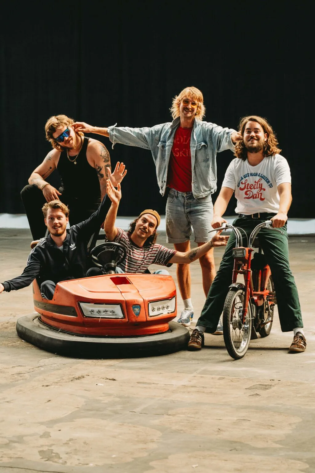 Vijf mannen met botsauto en fiets in loods.