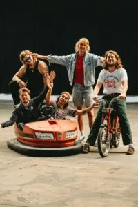 Vijf mannen met botsauto en fiets in loods.