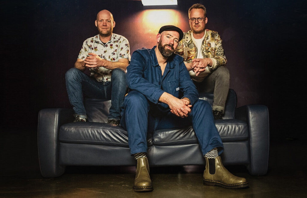 Drie mannen zittend op een blauwe bank