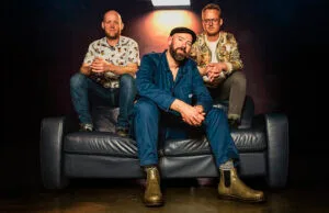 Drie mannen zittend op een blauwe bank