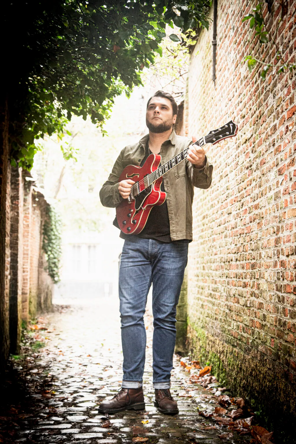 Man speelt gitaar in oude steeg.