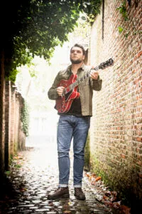 Man speelt gitaar in oude steeg.